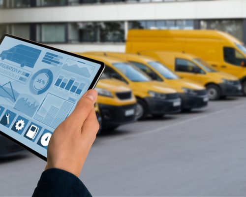 Manager,With,A,Digital,Tablet,On,The,Background,Of,Vans. Manager,With,A,Digital,Tablet,On,The,Background,Of,Vans.